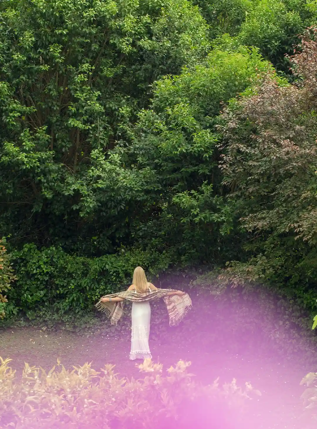 Maria José Martinez marchant dans son jardin, bras ouverts, dans un paysage naturel qui nourrit son inspiration artistique.