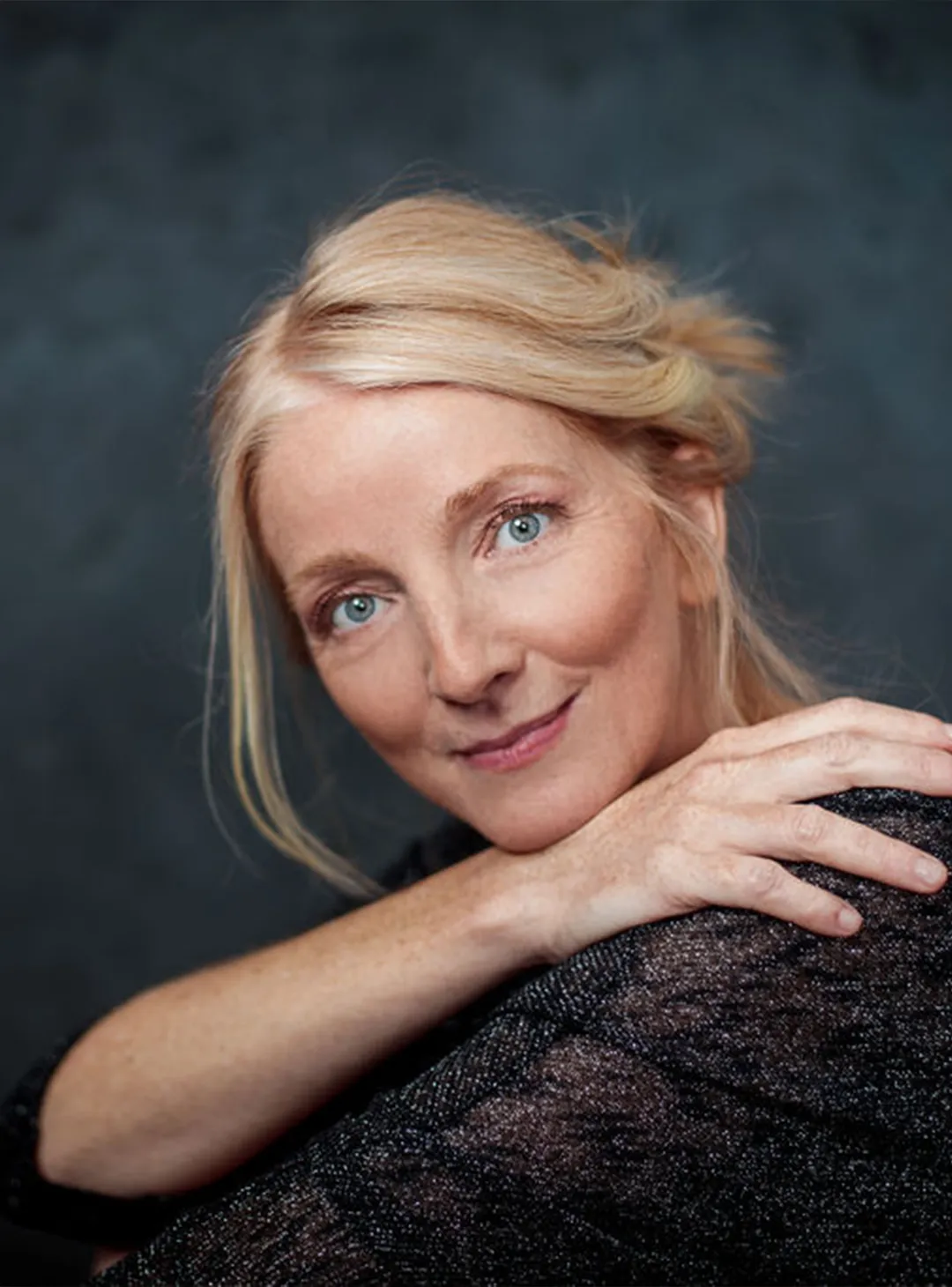 Portrait souriant de Maria José Martinez, artiste peintre, le menton posé sur sa main.